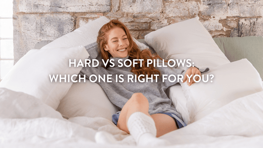 Person lying on bed surrounded by white pillows smiling 